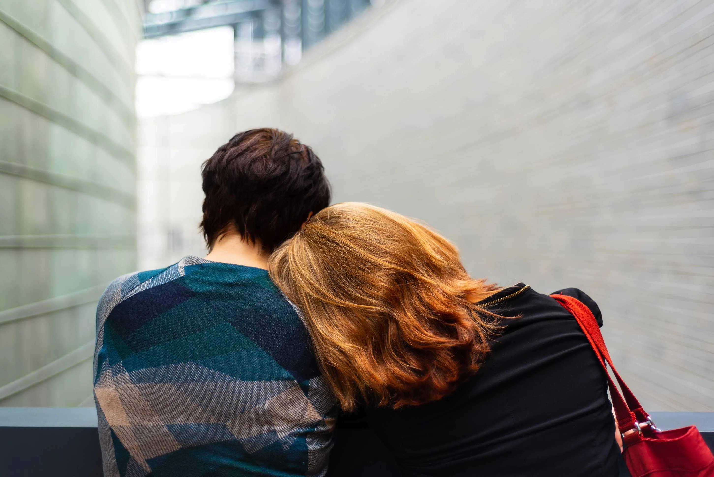 Two people sitting close on a quiet bench at dusk, representing connection and the possibility of relational healing